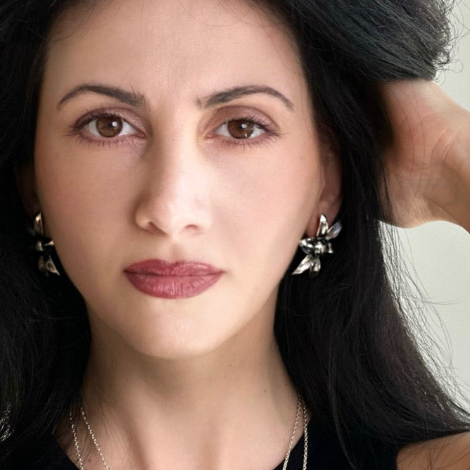 Woman with dark hair and floral earrings, wearing a black top.
